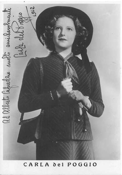 Fotografia dell'attrice in piedi con tailleur. Dedica e firma autografe …