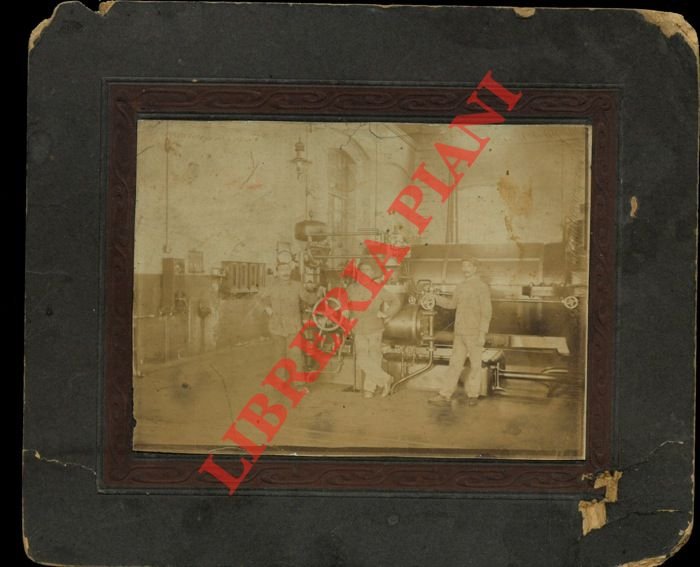 Interno d'officina con macchina utensile a vapore e tre operai …