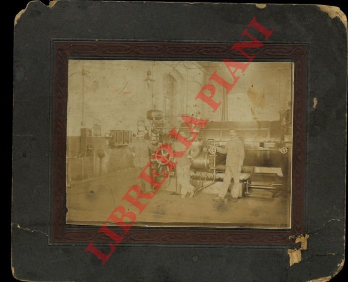 Interno d'officina con macchina utensile a vapore e tre operai …