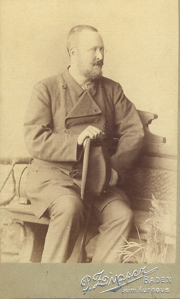 Ritratto fotografico di un uomo con barba e occhiali, seduto …
